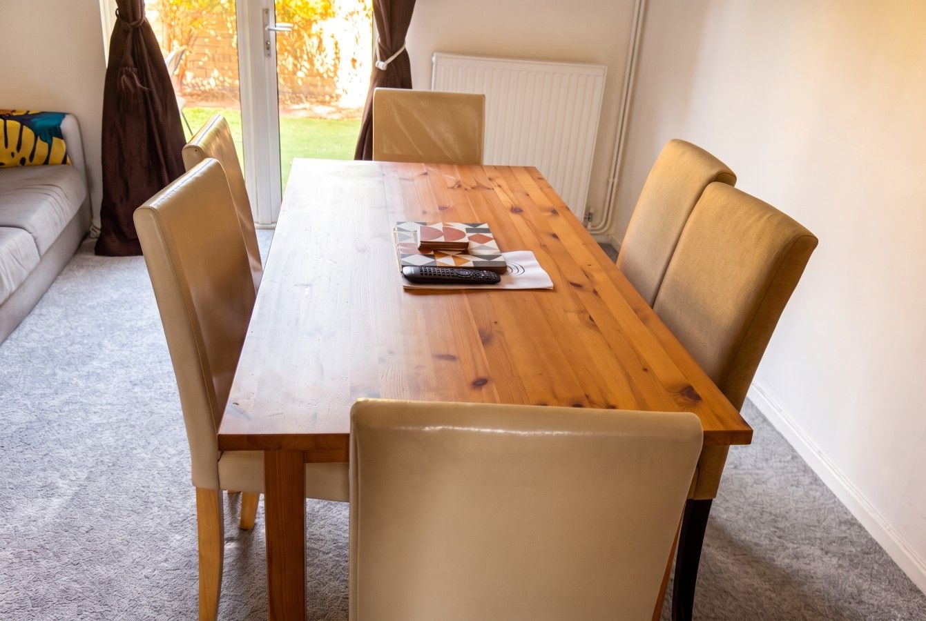 Une table de salle à manger en bois, quatre chaises, une télécommande et un set de table.