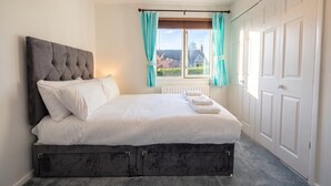 A bedroom with a large bed, a headboard, a window with curtains, and a door. - Pet-Friendly 3-Bed House with Garden · Sleeps 6 in Headington, Oxford (Headington)
