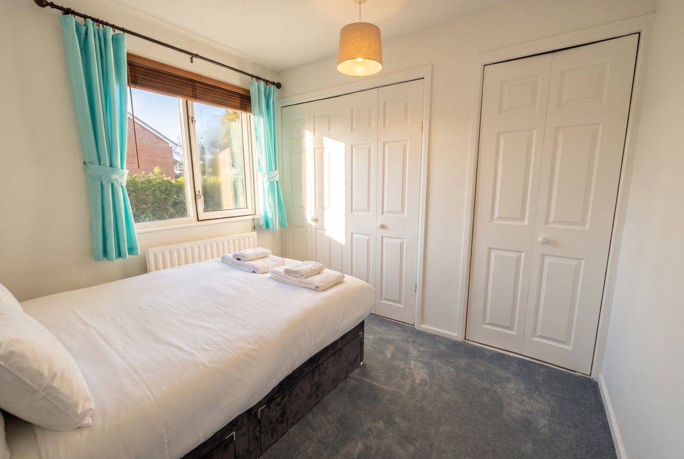 A bedroom with a bed, curtains, a radiator, and a door.