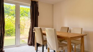 A dining area with a wooden table and chairs, a sliding glass door to the outdoors, and a ceiling light fixture. - Pet-Friendly 3-Bed House with Garden · Sleeps 6 in Headington, Oxford (Headington)
