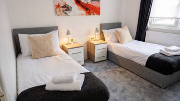 A hotel room with two beds, bedside tables, lamps, and a large abstract painting on the wall.
