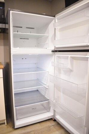 A white refrigerator with multiple shelves and a freezer compartment. - Bishop’s Place. (Winnipeg)