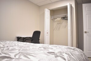Ein Hotelzimmer mit Bett, Schreibtisch und Stuhl. Ein Kleiderschrank mit Kleiderbügeln ist ebenfalls vorhanden.