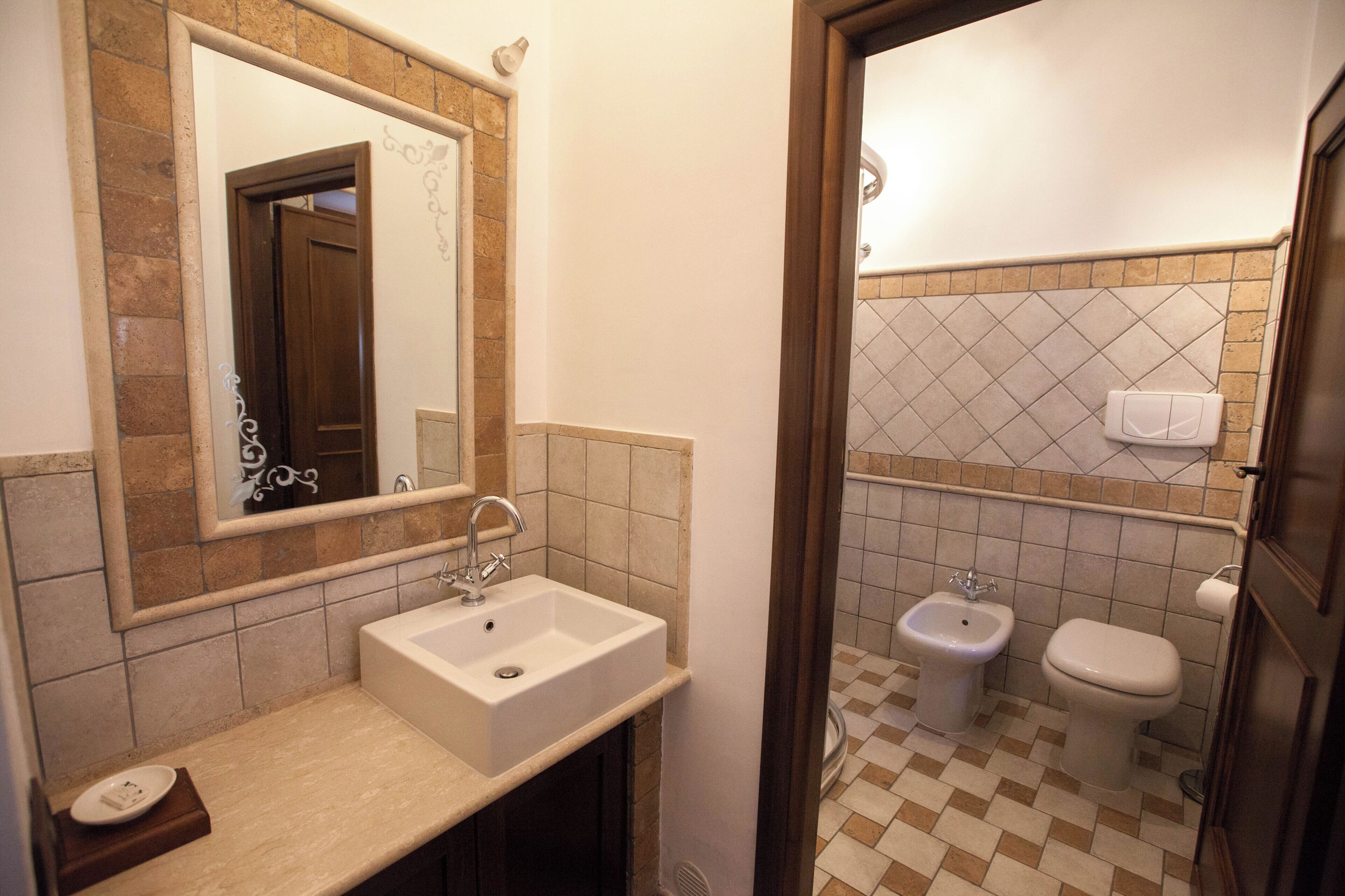 Een badkamer met een wastafel, spiegel en twee toiletten.