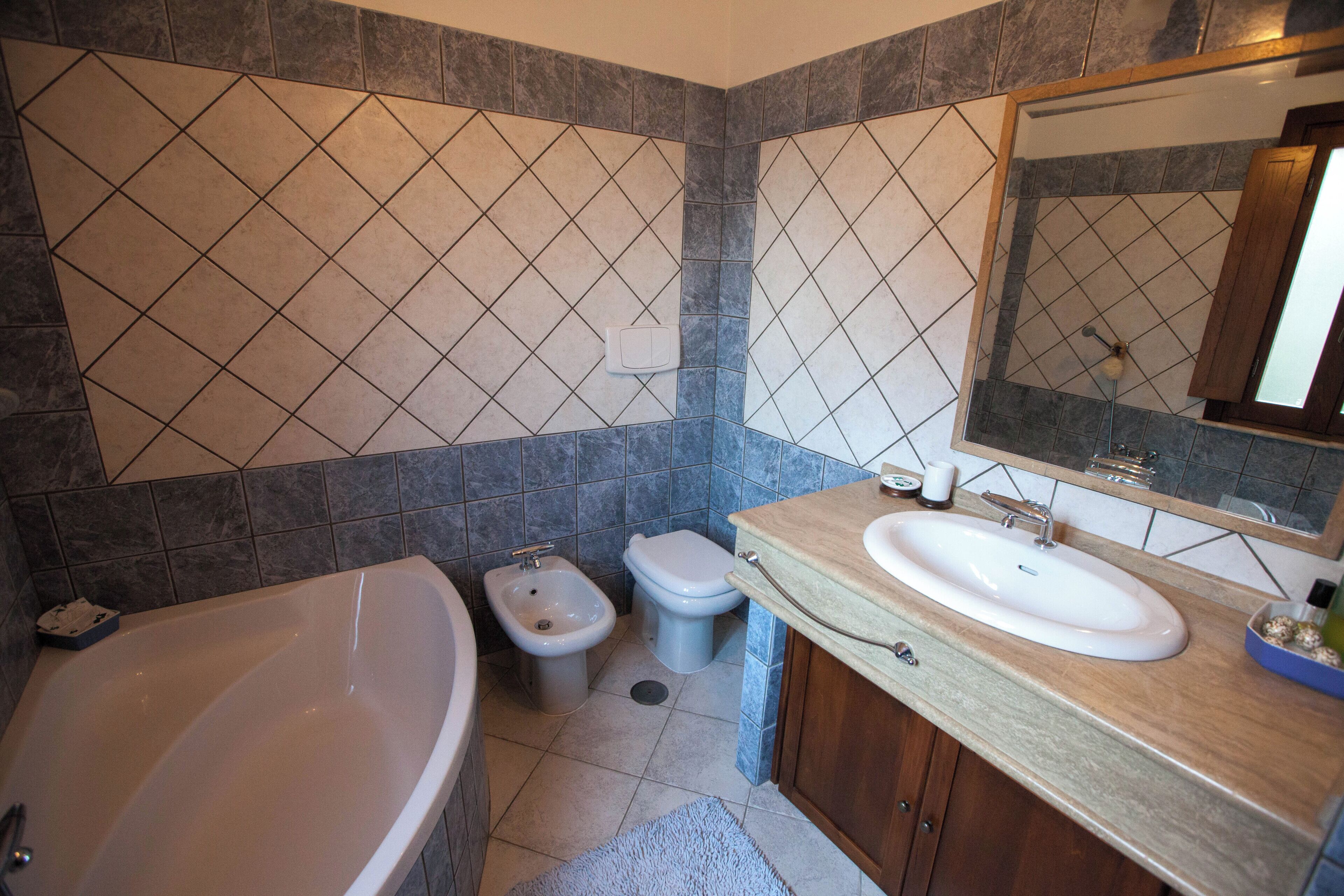 A bathroom with a bathtub, two sinks, a bidet, and a mirror.