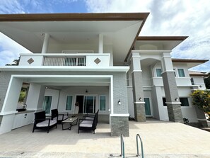 A modern two-story house with a covered patio area, outdoor furniture, and a visible staircase leading to the upper floor. - Panoramic Sunset View Private Pool Villa, Maikhao beach (Thalang)