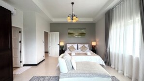 Quarto de hotel com cama, mesa de cabeceira, luminária, quadro na parede e vista para o exterior pela janela.