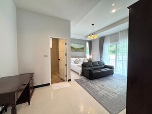 A modern hotel room with a bed, a sofa, a desk, and a large window.