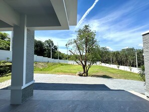 A modern building with a covered outdoor area, a paved patio, and a tree.