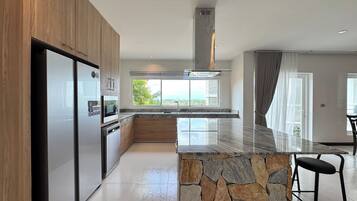 A modern kitchen with a stone island, built-in appliances, and a view to the outdoors.