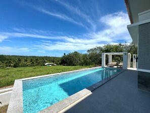 A rectangular swimming pool with a clear blue water surface, surrounded by a paved deck.