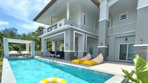 Uma casa moderna de dois andares com piscina, área de estar externa e um alpendre coberto.