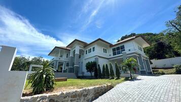 A two-story house with a stone retaining wall and a paved driveway.
