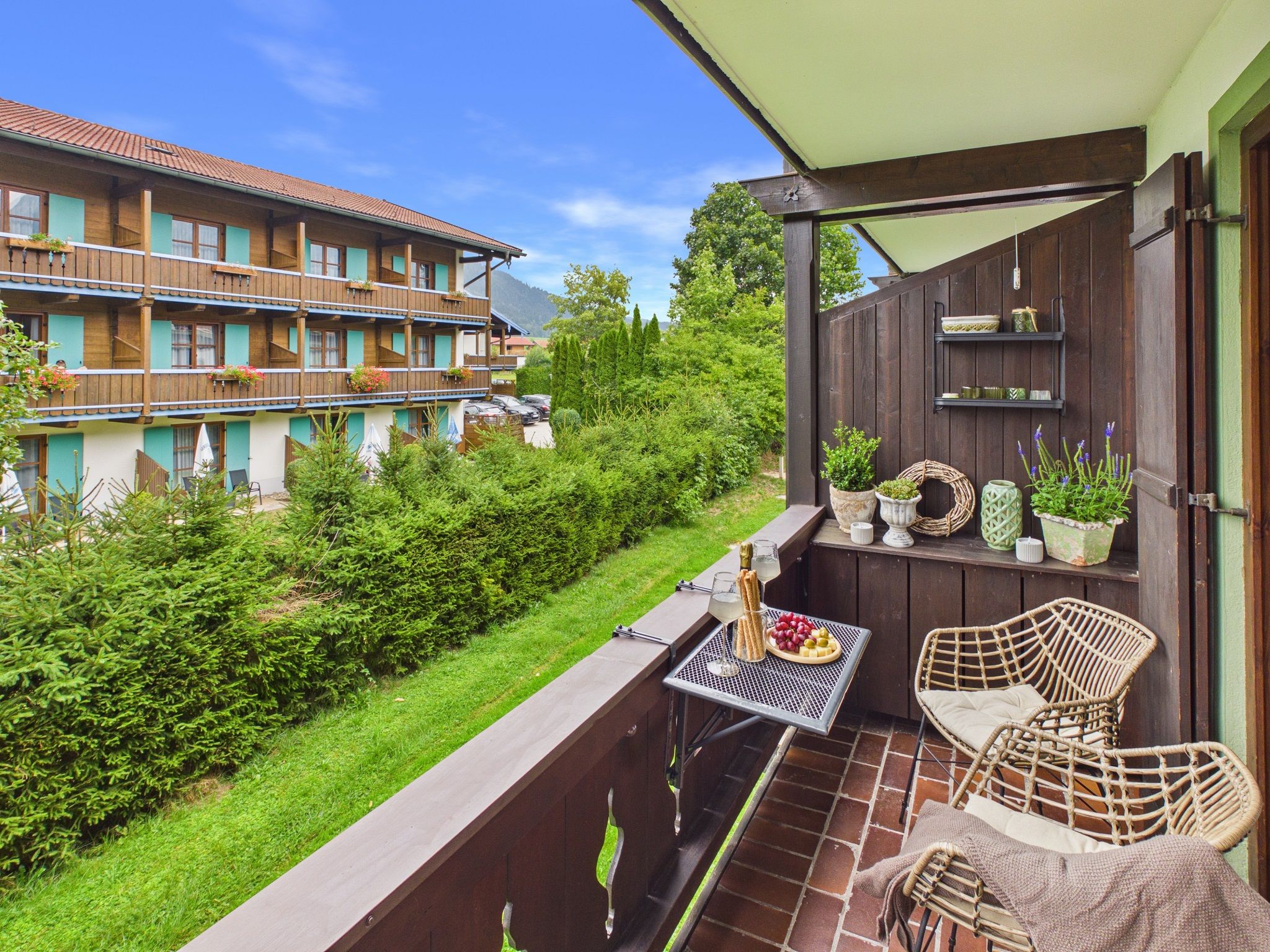 Un balcon avec une table dressée pour le dîner, des sièges d’extérieur et une vue sur un immeuble doté de nombreux balcons.