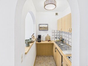 A compact kitchen with a coffee maker, a sink, and a small countertop.