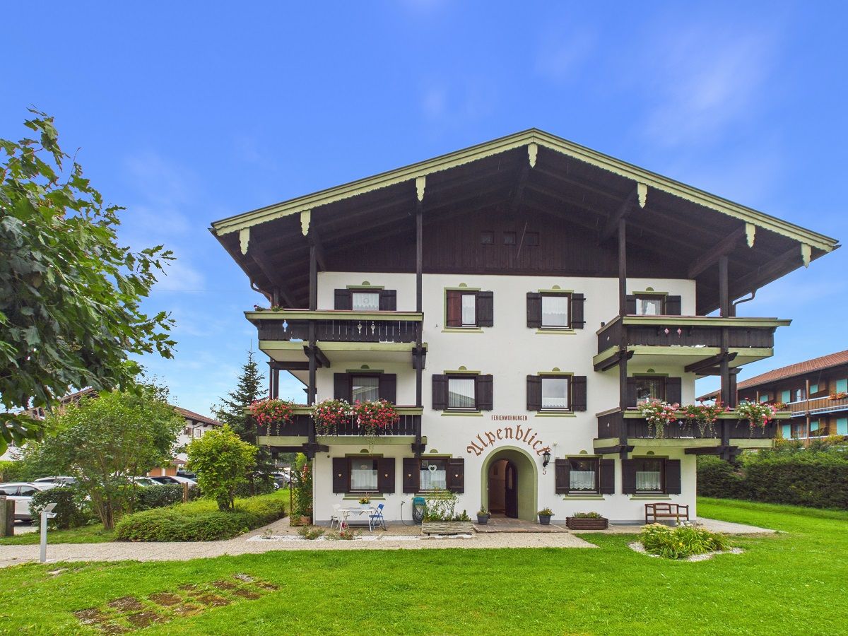 Ein mehrstöckiges Hotel mit Balkonen, einem zentralen Eingang und einem gepflegten Rasen.