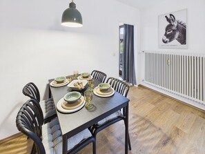 A dining area with a table set for four, chairs, a pendant light, and a radiator. - Vacation rental for 4 people, 1 separate bedroom, balcony, 54 m² (Inzell)
