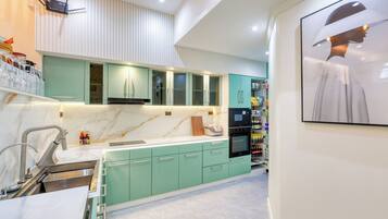 Una cocina moderna con armarios azul verdoso, encimera de mármol y horno empotrado.