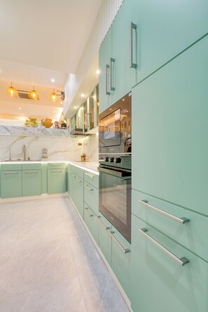 Una cocina moderna con armarios color aguamarina, electrodomésticos de acero inoxidable y encimera de mármol.