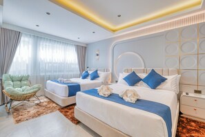 Habitación de hotel con dos camas, un área de descanso y un ventanal grande.