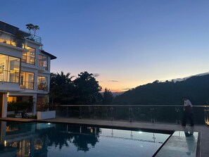 A modern two-story building with a glass balcony overlooking a swimming pool. - Smith & Appy Luxury Seaview Penthouse (Koh Samui)