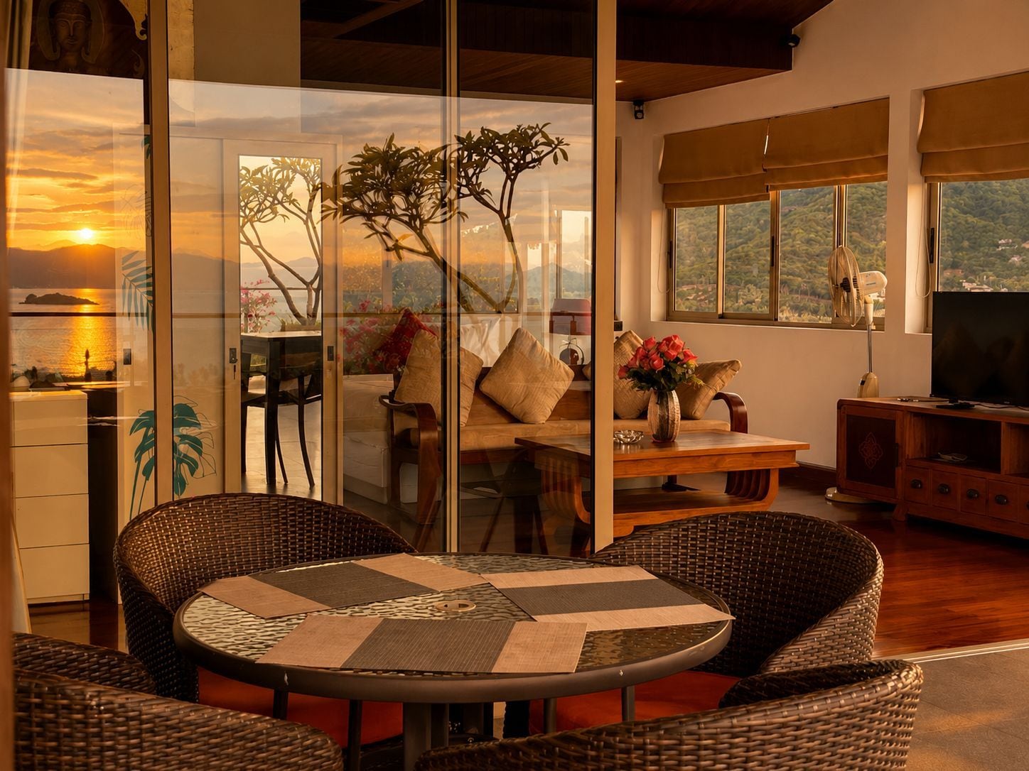 A room with a dining table, chairs, a sofa, a TV, and a view of the outdoors.