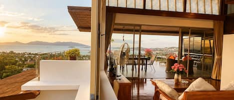 Un interior moderno con un balcón que ofrece vistas panorámicas del mar y las montañas.