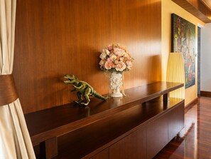 A reception desk with a wooden finish, a vase with flowers, and a dinosaur figurine. - Smith & Appy Luxury Seaview Penthouse (Koh Samui)
