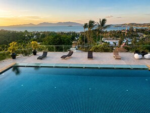 A swimming pool with lounge chairs and a view of a coastal town. - Smith & Appy Seaview Penthouse (Koh Samui)