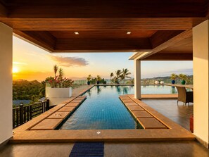 Una piscina con vistas a la puesta de sol y palmeras.