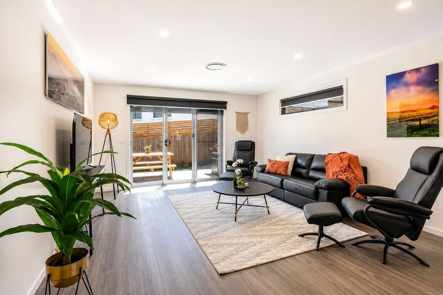 A modern living room with a sofa, chairs, a coffee table, and a TV.