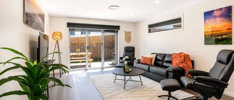 A modern living room with a sofa, chairs, a coffee table, and a TV.