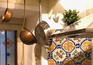 A kitchen with hanging pots, a potted plant, and a decorative tile backsplash. - AthaHome Deluxe - Designer Apartment in the Heart of Palermo (Palermo)