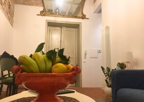 A room with a red bowl on a table, a chair, a door, and a lamp. - AthaHome Deluxe - Designer Apartment in the Heart of Palermo (Palermo)