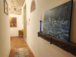 A hallway with a tiled floor, a painting on the wall, and a small table with a chair. - AthaHome Deluxe - Designer Apartment in the Heart of Palermo (Palermo)