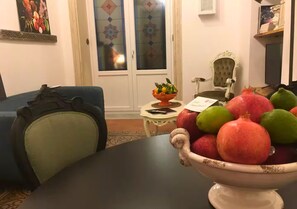 A dining area with a table set for two, a decorative bowl of fruit, and a blue armchair. - AthaHome Deluxe - Designer Apartment in the Heart of Palermo (Palermo)