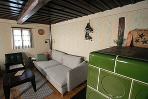 A living room with a sofa, a small table, a green appliance, and a window with curtains.