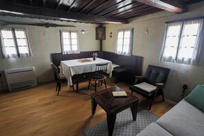 A room with a dining table, chairs, a sofa, and a wooden floor.