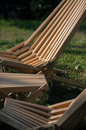 Two wooden lounge chairs with metal frames, positioned on grass.