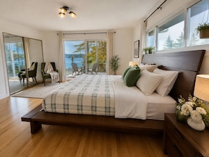 Une chambre moderne avec un grand lit, une vue sur l’extérieur et un coin salon avec des fauteuils.