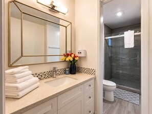 Une salle de bain équipée d’un lavabo, d’un miroir et d’un espace douche.