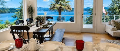 Un coin repas avec vue sur un lac, une table à manger dressée avec des assiettes et des verres, et un banc.