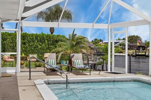 A pool area with lounge chairs and a covered seating area. - Hibiscus Hideaway – Tropical Waterfront Paradise Villa 26 (Cape Coral)
