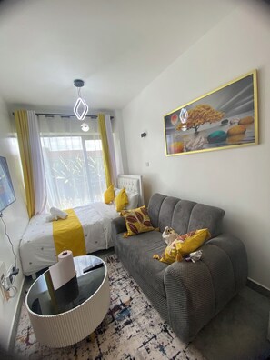 Ett hotellrum med en säng, en soffa, en tavla och ett fönster med gardiner.