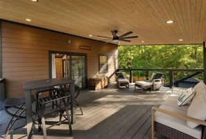 A covered outdoor area with a table and chairs, a sofa, and a ceiling fan.