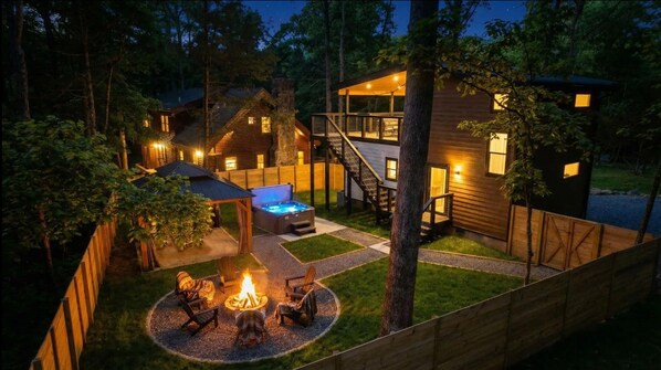 A wooden cabin with a hot tub, outdoor seating, and a fire pit.