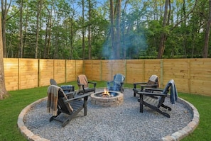 A circular outdoor seating area with a fire pit, surrounded by a gravel border and wooden benches. - New- Hot tub, firepit, fenced-in yard, near the Smoky Mountain National Park! (Gatlinburg)