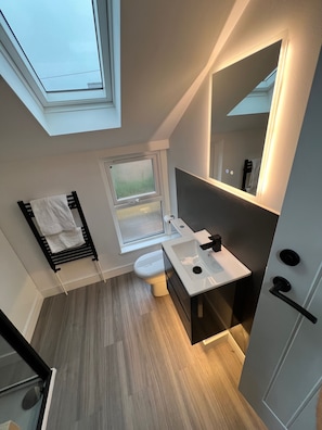 Un baño moderno con tragaluz, inodoro, lavabo y perchero para toallas.