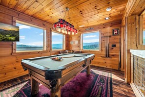 A pool table in a wooden room with large windows, a ceiling fan, and a view of the outdoors. - Thunder Bear Ridge | Mountain Views & Hot Tub (Sevierville)