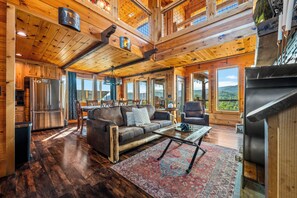 A spacious living area with a large wooden ceiling, a modern kitchen, and a view of the outdoors. - Thunder Bear Ridge | Mountain Views & Hot Tub (Sevierville)